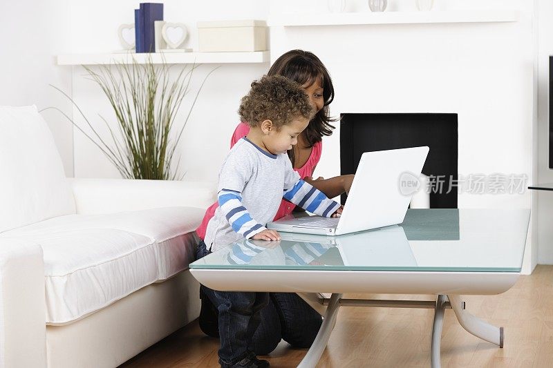 非裔美国母亲/保姆和混血儿蹒跚学步使用笔记本电脑